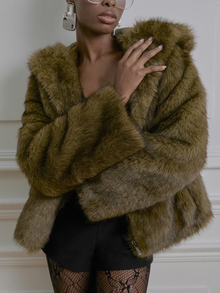 Manteau court en éco-fourrure avec une fermeture éclair et une capuche