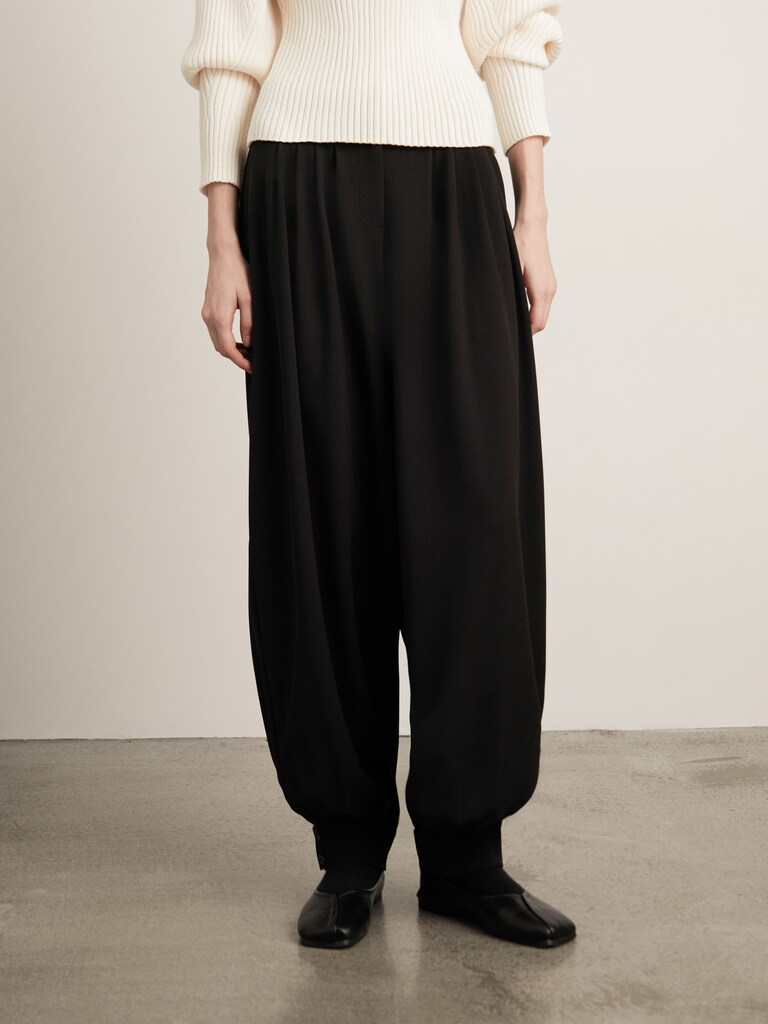 Loose-fitting trousers with pleats at the waist and fitted cuffs